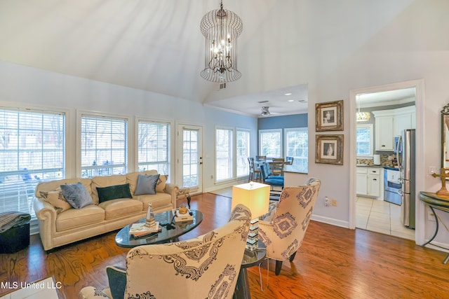 living room featuring ceiling fan with notable chandelier, high vaulted ceiling, and light hardwood / wood-style flooring