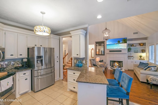 kitchen featuring pendant lighting, decorative backsplash, dark stone countertops, appliances with stainless steel finishes, and white cabinetry