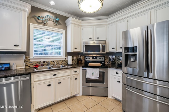 kitchen with white cabinetry, sink, stainless steel appliances, dark stone counters, and light tile patterned floors