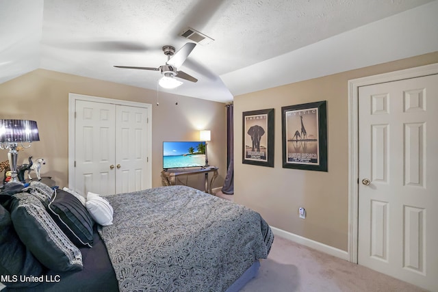 carpeted bedroom featuring a textured ceiling, a closet, vaulted ceiling, and ceiling fan