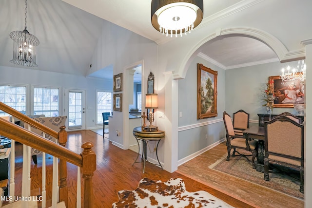 interior space with a notable chandelier, lofted ceiling, wood-type flooring, and crown molding