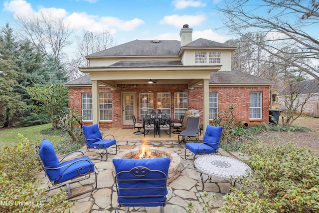 back of property featuring ceiling fan, a patio, and an outdoor fire pit