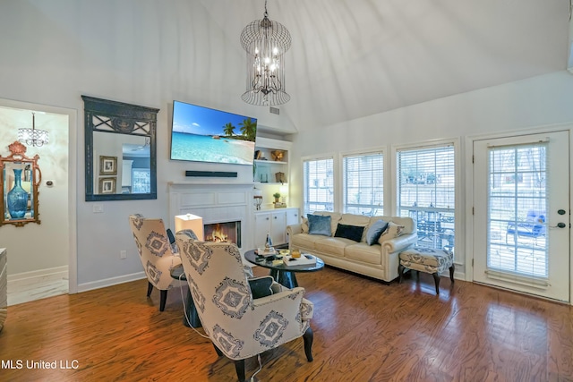 living room featuring plenty of natural light, wood-type flooring, built in features, and an inviting chandelier