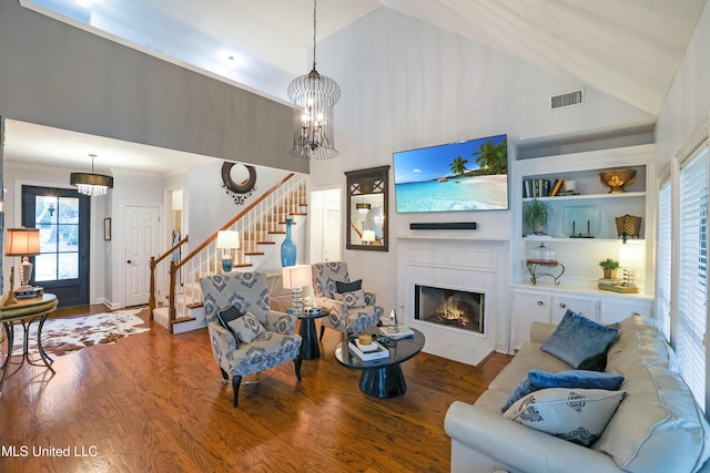 living room featuring built in shelves, high vaulted ceiling, hardwood / wood-style flooring, and an inviting chandelier