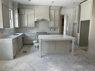 kitchen with backsplash, a breakfast bar, a kitchen island, and premium range hood