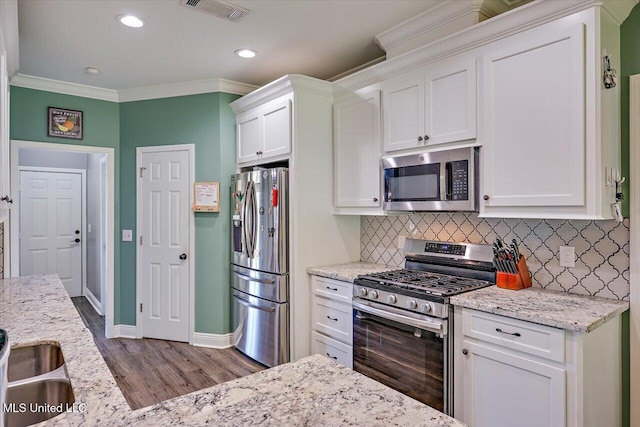 kitchen with visible vents, wood finished floors, baseboards, stainless steel appliances, and white cabinetry