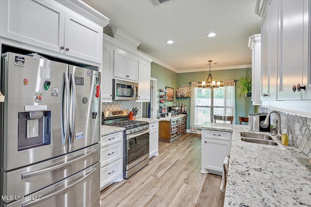 kitchen with white cabinets, stainless steel appliances, a notable chandelier, and a sink