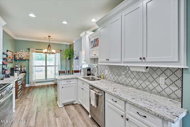 kitchen featuring white cabinets, stainless steel appliances, an inviting chandelier, and a sink