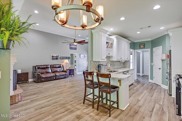 kitchen with freestanding refrigerator, white cabinetry, baseboards, visible vents, and ornamental molding
