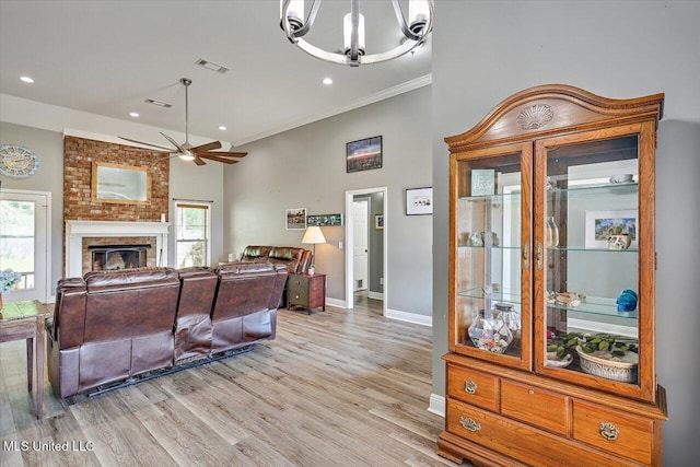living area featuring visible vents, plenty of natural light, ornamental molding, and ceiling fan with notable chandelier