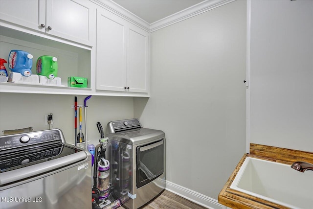 laundry room with cabinet space, crown molding, separate washer and dryer, baseboards, and wood finished floors