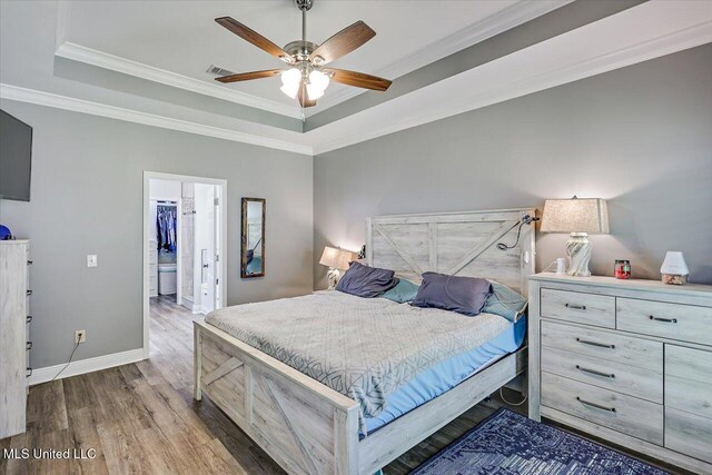 bedroom with a raised ceiling, baseboards, wood finished floors, and visible vents