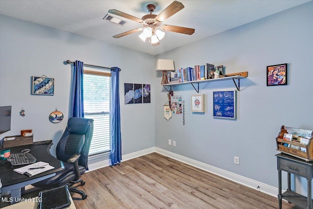 office featuring baseboards, ceiling fan, wood finished floors, and visible vents