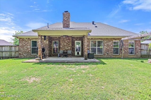 back of house with a yard, a ceiling fan, fence, and a chimney