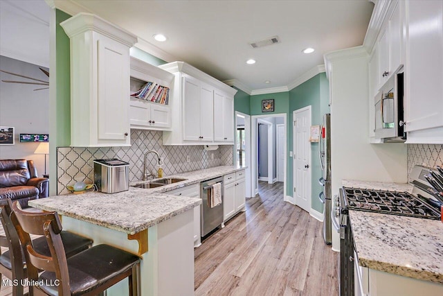kitchen with appliances with stainless steel finishes, a sink, white cabinetry, decorative backsplash, and visible vents