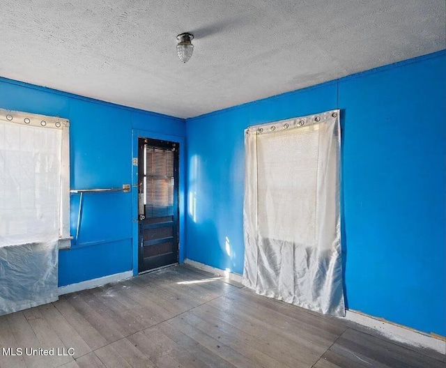 unfurnished room with hardwood / wood-style flooring and a textured ceiling