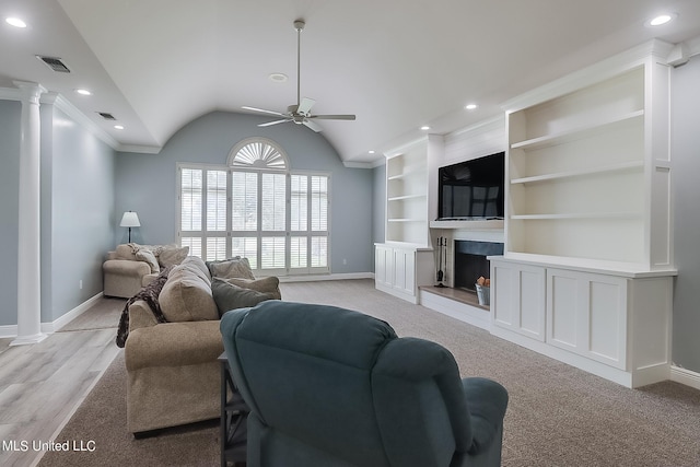 living room featuring vaulted ceiling, ornamental molding, built in features, ceiling fan, and decorative columns