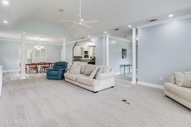 carpeted living room featuring ceiling fan with notable chandelier, vaulted ceiling, ornamental molding, and ornate columns