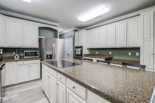 kitchen with white cabinetry, ornamental molding, stainless steel appliances, and a kitchen island