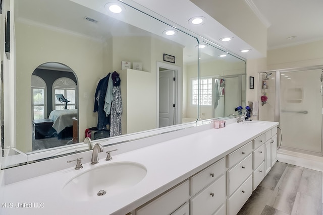 bathroom with ornamental molding, hardwood / wood-style floors, vanity, and a shower with shower door