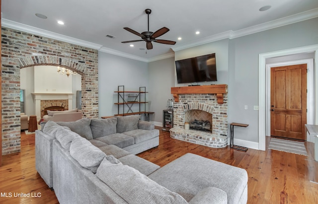 living room with light hardwood / wood-style floors, crown molding, a fireplace, and ceiling fan