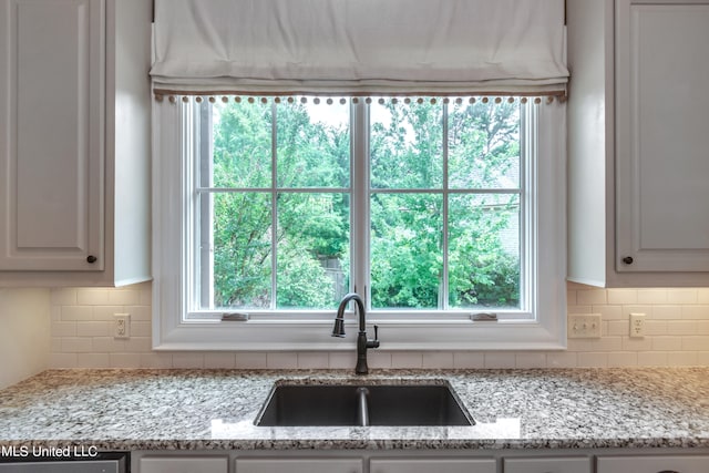 kitchen featuring white cabinetry, light stone countertops, and sink