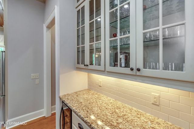 kitchen with tasteful backsplash, light stone countertops, light wood-type flooring, and beverage cooler