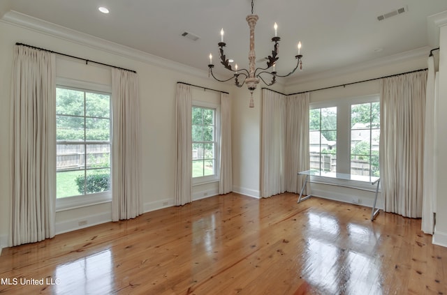 empty room with ornamental molding, a notable chandelier, and light hardwood / wood-style floors