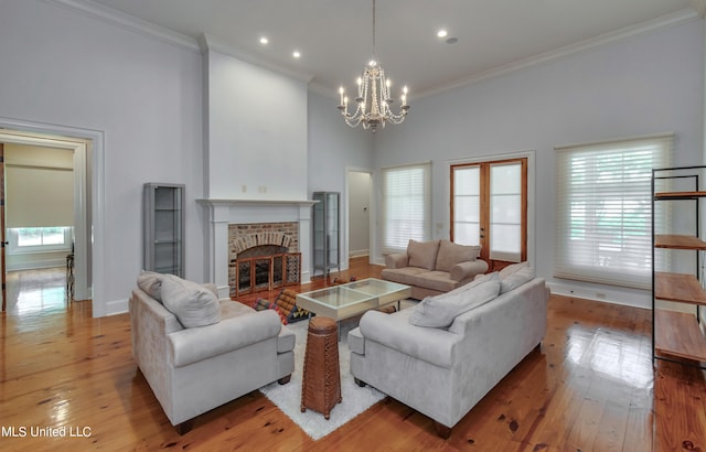 living room featuring a towering ceiling, a fireplace, light hardwood / wood-style floors, and plenty of natural light