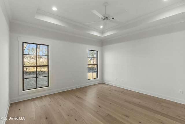 unfurnished room featuring a raised ceiling, ornamental molding, ceiling fan, and light hardwood / wood-style floors