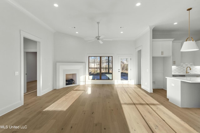 unfurnished living room with ornamental molding, ceiling fan, and light hardwood / wood-style flooring