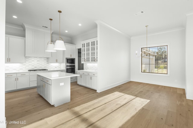 kitchen featuring white cabinetry, a center island, hanging light fixtures, stainless steel microwave, and black gas cooktop