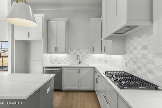 kitchen with premium range hood, appliances with stainless steel finishes, decorative light fixtures, white cabinetry, and sink