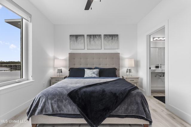 bedroom with ceiling fan, ensuite bath, and light wood-type flooring