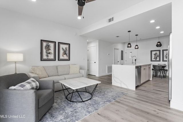 living room with sink, ceiling fan, and light wood-type flooring