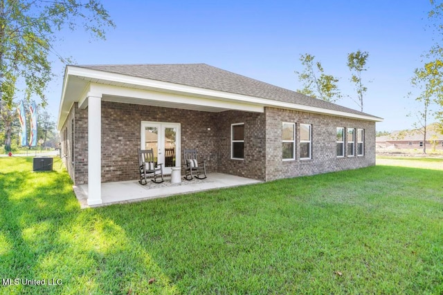 rear view of house featuring central AC unit, a lawn, a patio, and french doors