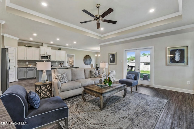 living room featuring dark hardwood / wood-style flooring, ceiling fan, a raised ceiling, crown molding, and french doors