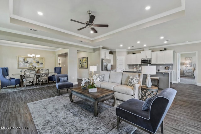 living room with a raised ceiling, ornamental molding, dark hardwood / wood-style floors, and ceiling fan with notable chandelier