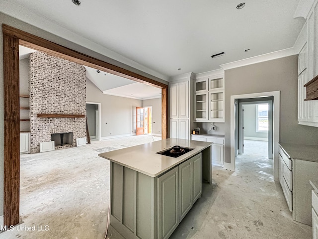501 Harper Cv, Flowood, MS 39232 - kitchen featuring a center island, a tiled fireplace, lofted ceiling, white cabinetry, and glass insert cabinets