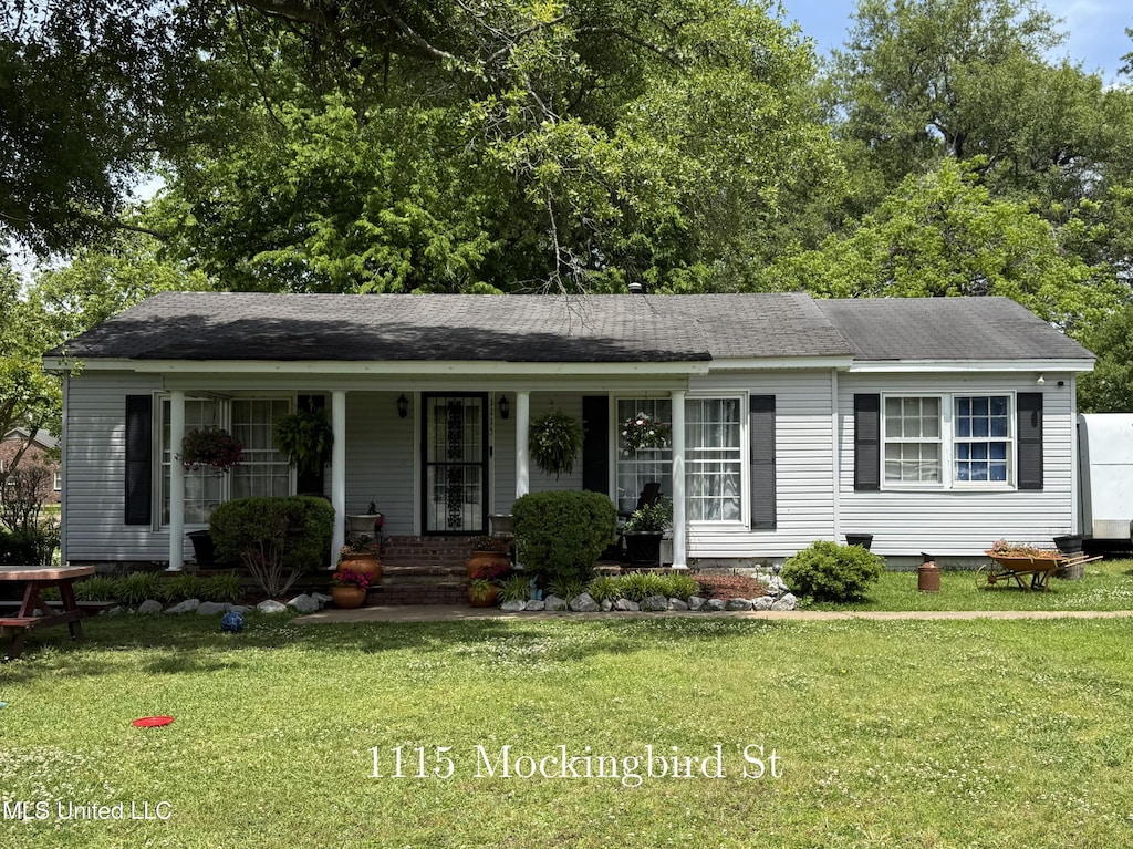 ranch-style house featuring covered porch, a front lawn, and roof with shingles