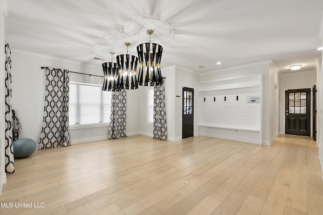 workout room featuring light hardwood / wood-style flooring, ornamental molding, and an inviting chandelier