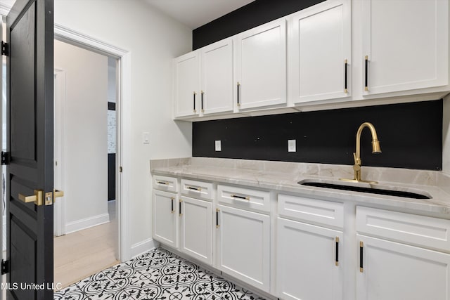 kitchen with sink, white cabinets, and light stone countertops