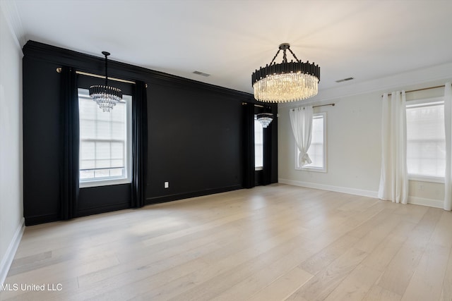 unfurnished room with a notable chandelier, light wood-type flooring, and crown molding