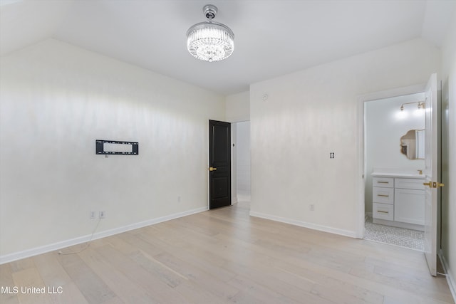 empty room with light hardwood / wood-style floors and an inviting chandelier