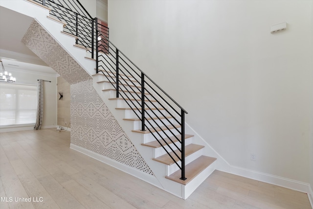 stairway with a notable chandelier, crown molding, and wood-type flooring