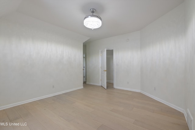 unfurnished room with an inviting chandelier and light wood-type flooring