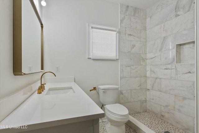 bathroom featuring vanity, toilet, and tiled shower