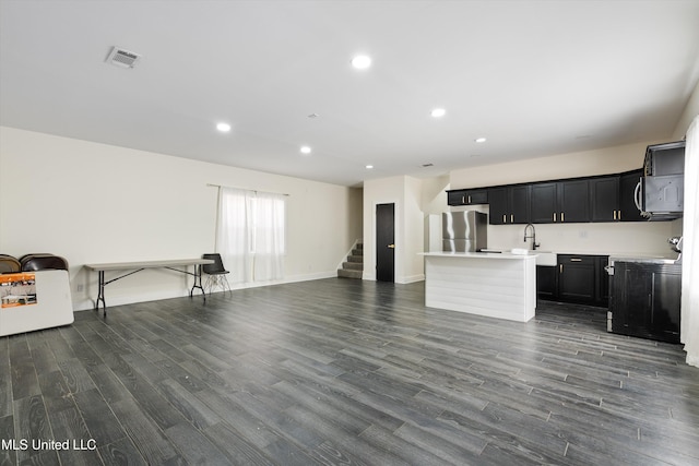 kitchen featuring stove, an island with sink, dark hardwood / wood-style floors, and stainless steel refrigerator