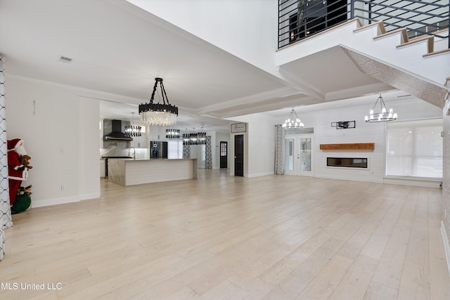 living room with light hardwood / wood-style floors, ornamental molding, and an inviting chandelier