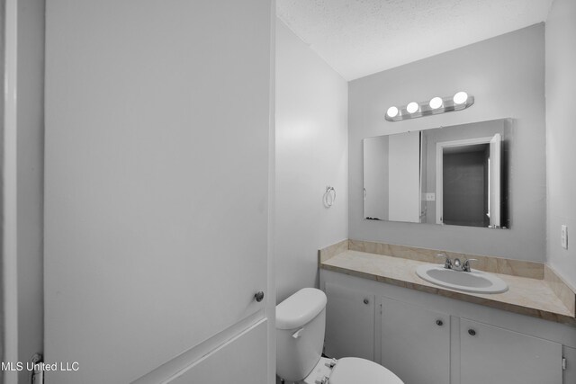 bathroom with toilet, a textured ceiling, and vanity